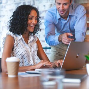 Two professionals smiling and working on a laptop during a customer support session for internet service.