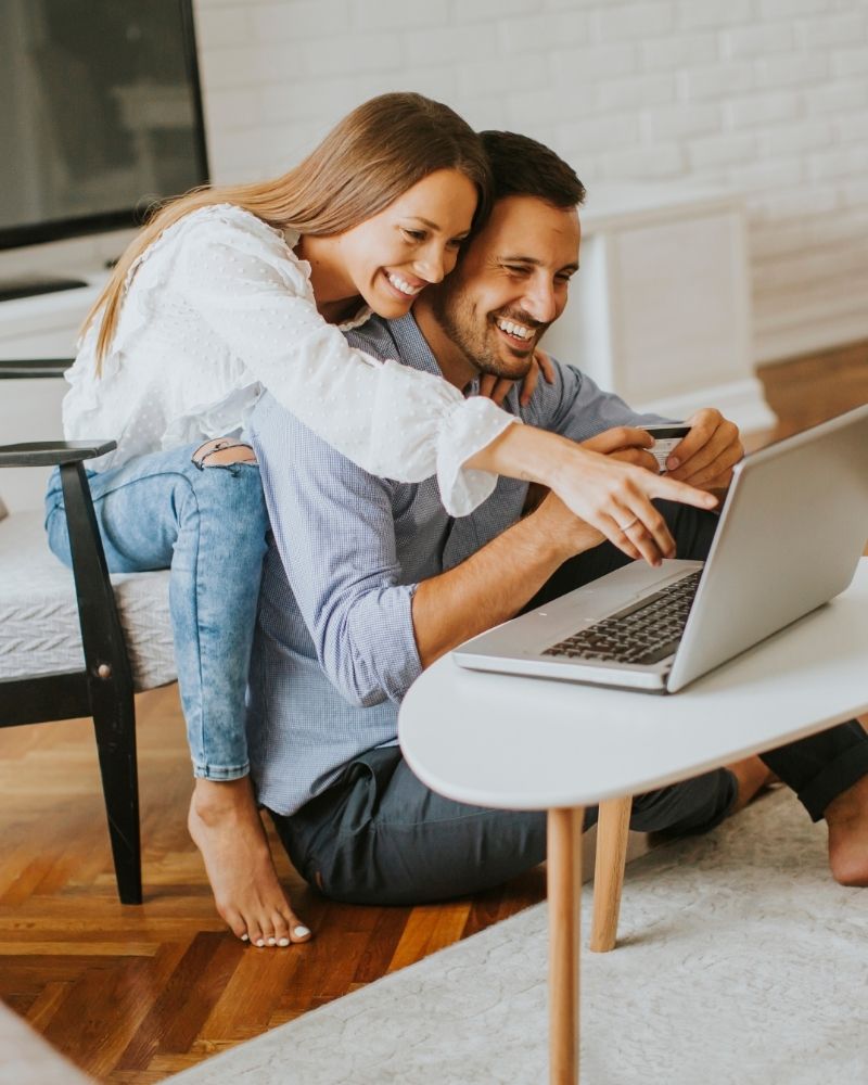 Smiling couple using laptop together at home with fast and reliable MetaLINK internet