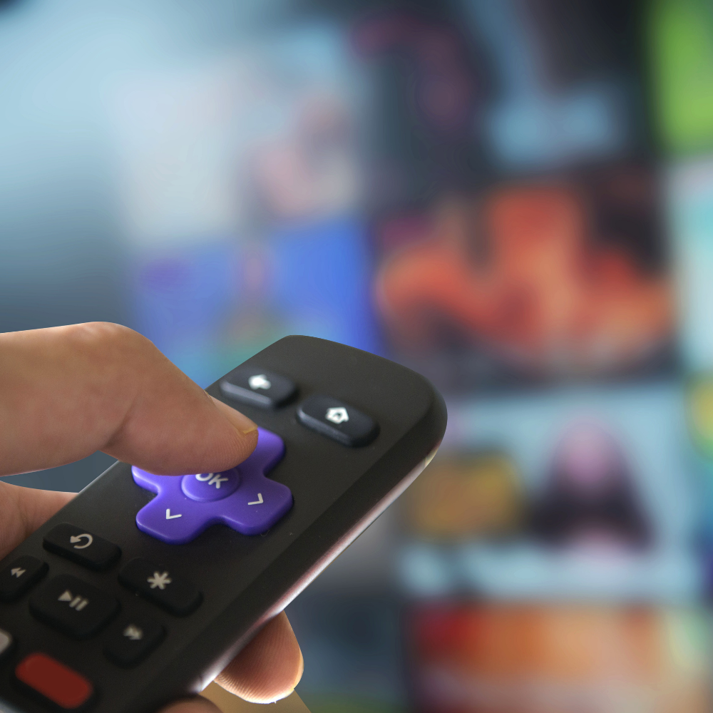 Hand using a Roku remote in front of a streaming TV interface, representing MetaLINK’s flexible internet and TV service options