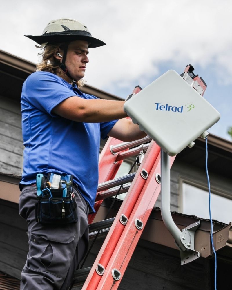 MetaLINK technician installing a wireless internet receiver on a residential rooftop