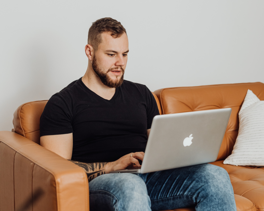 Man sitting on a couch using a laptop to browse MetaLINK internet services at home
