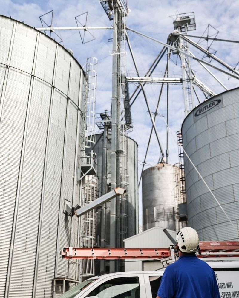 MetaLINK technician inspecting wireless tower near grain bins for rural internet coverage
