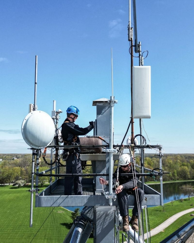 Technicians installing wireless equipment on a tall communication tower for MetaLINK upgrade