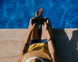 Person relaxing by a swimming pool while streaming content on a smartphone using reliable high-speed internet