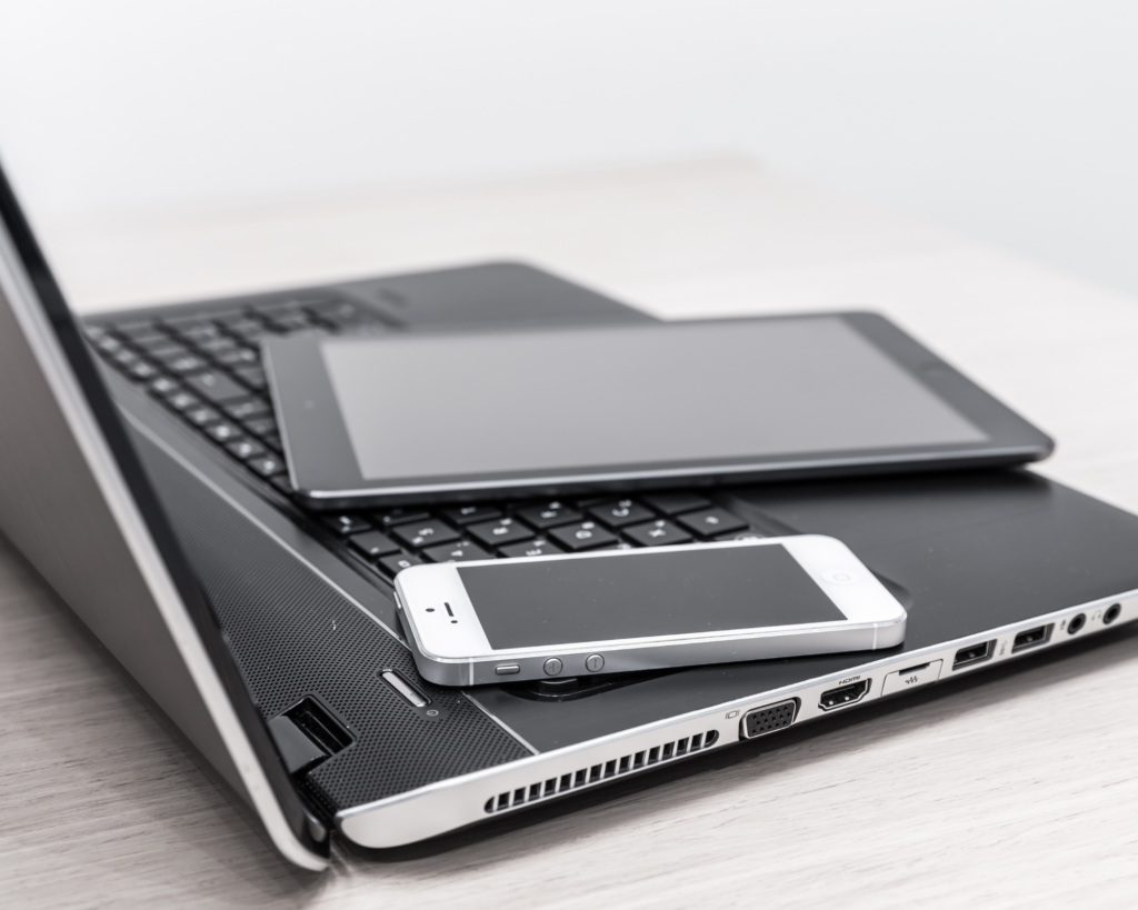 Laptop, tablet, and smartphone resting together on a desk, representing multiple devices connected to home internet