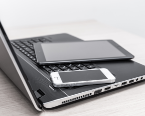 Laptop, tablet, and smartphone resting together on a desk, representing multiple devices connected to home internet